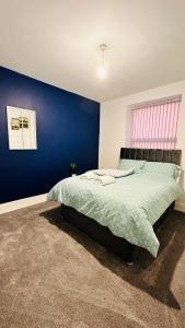 a bedroom with a bed with a blue wall at UR PLACE in Manchester