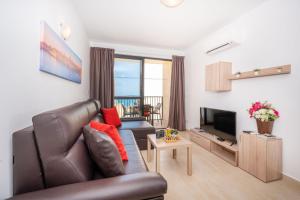 un soggiorno con divano e TV di Sea Bliss Apartments with terrace just off seafront in St Paul's Bay - By Getawaysmalta a San Pawl il-Baħar