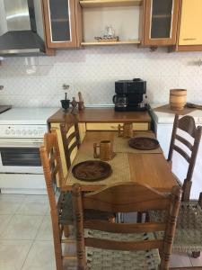 a kitchen with a wooden table with chairs and a microwave at LITHOS Porto Kagio in Pórto Káyio