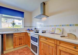 a kitchen with wooden cabinets and a sink and a window at High Tides in Crafthole