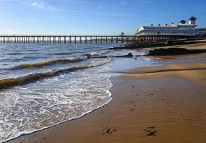 a beach with a pier and the ocean at Beautiful 6 Berth Caravan At Suffolk Sands Holiday Park Ref 45010mv in Felixstowe