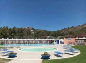 a large swimming pool with blue chairs and a resort at Casa l’orizzonte azzurro in Pula