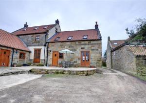 een oud stenen huis met een tafel en een paraplu bij Westlands Cottage in Mickleby