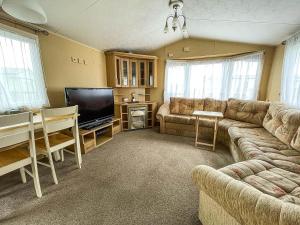 a living room with a couch and a flat screen tv at Great 6 Berth Caravan With Decking By The Beach In Suffolk Ref 40023nd in Lowestoft