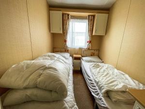 two beds in a small room with a window at Great 6 Berth Caravan With Decking By The Beach In Suffolk Ref 40023nd in Lowestoft