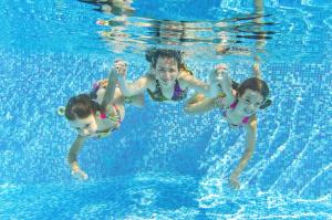 a man and two children swimming in a swimming pool at Lovely 6 Berth Caravan At Coopers Beach Park In Essex Ref 49075p in East Mersea