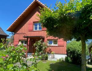 una casa roja con un árbol delante en Doppelzimmer in charmantem B&B, en Hemberg