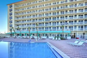 a hotel with a swimming pool in front of a building at Harbour Beach Resort in Daytona Beach