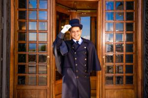Een man in een diploma-uitreikingsuniform die voor een deur staat. bij Grand Hotel Parker's in Napels