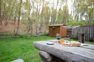 a wooden picnic table with a glass of wine and bread at Bracken House in Aviemore