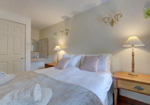 a bedroom with two beds and a table with a lamp at West Cottage in Thwaite