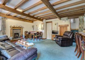 sala de estar con muebles de cuero y chimenea en West Cottage en Thwaite