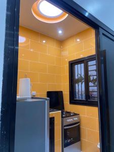 a yellow kitchen with a stove and a refrigerator at Dakar-Sénégal mini studio chambre toilette cuisine in Dakar