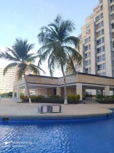 a building with palm trees in front of a swimming pool at Ocean Blue in Porlamar