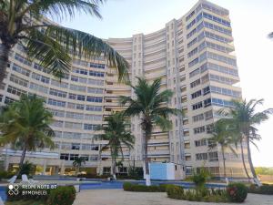 a large building with palm trees in front of it at Margarita & More, Ocean in Porlamar