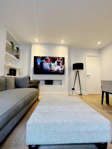 uma sala de estar com um sofá e uma televisão na parede em Londwell, Luxe and Leaves, Chelsea Flat with Private Garden em Londres