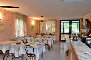 un ristorante con tavoli e sedie bianchi in una stanza di Hotel Fiordaliso a Sirmione