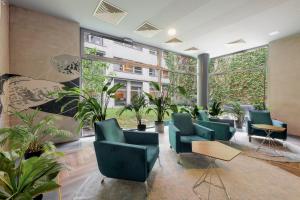 a waiting room with green chairs and plants at Bliss Residence & Spa in Budapest