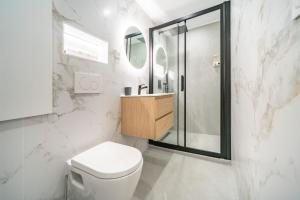 La salle de bains blanche est pourvue d'une douche et de toilettes. dans l'établissement Hypercentre - 5mn à pied Monaco - AQ, à Beausoleil