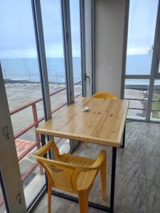 a wooden table and chairs in a room with windows at Magnetic Sand Hotel in Ureki