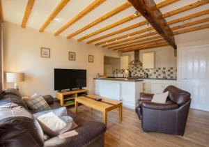 uma sala de estar com um sofá, uma televisão e uma mesa em Weavers Cottage em Cowling