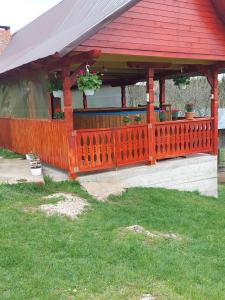 a wooden gazebo with a red roof at Cabana Gabriela in Gîrda de Sus