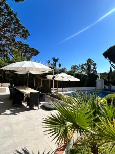 eine Terrasse mit Tischen und Sonnenschirmen neben einem Pool in der Unterkunft Royal Course Villa, Vale do Lobo in Vale do Lobo