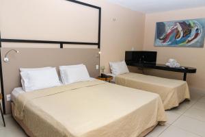 um quarto de hotel com duas camas e uma televisão em Fórmula Arrey Hotel - Teresina em Teresina