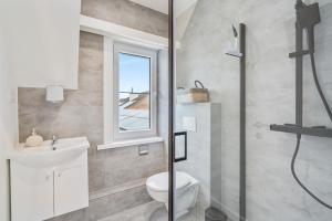 een badkamer met een toilet, een wastafel en een raam bij maison des dunes in Oostende