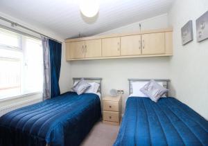 a bedroom with two beds with blue sheets and a window at Waters Edge in Routh