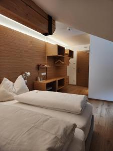 a bedroom with a large white bed and a desk at Hotel Dolomiten in Dobbiaco