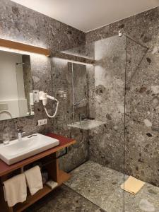 a bathroom with a sink and a shower at Hotel Dolomiten in Dobbiaco