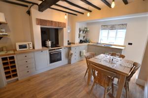 uma cozinha com uma mesa de madeira e uma sala de jantar em The Old Tailors Cottage em Long Whatton