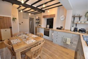 uma grande cozinha com uma mesa de madeira e uma mesa e cadeiras em The Old Tailors Cottage em Long Whatton