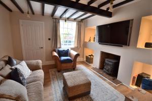 a living room with a couch and a tv at The Old Tailors Cottage in Long Whatton