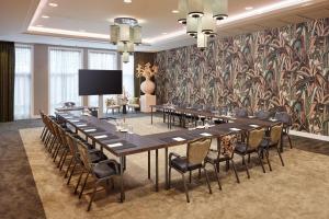 ein großer Konferenzraum mit einem langen Tisch und Stühlen in der Unterkunft Van der Valk Palace Hotel Noordwijk in Noordwijk aan Zee