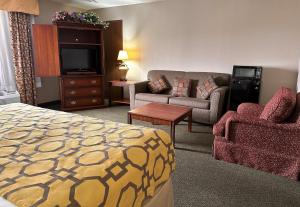 um quarto de hotel com uma cama, um sofá e uma televisão em Baymont by Wyndham Corydon em Corydon