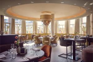 ein Restaurant mit Tischen, Stühlen und Fenstern in der Unterkunft Van der Valk Palace Hotel Noordwijk in Noordwijk aan Zee