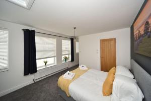 麥克爾斯菲爾德的住宿－Pinfold Suite - Chester Road Apartments By，一间卧室设有一张大床和两个窗户。