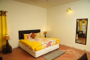 a bedroom with a bed with yellow sheets and a mirror at Copperhill- A Luxury Homestay in Madikeri