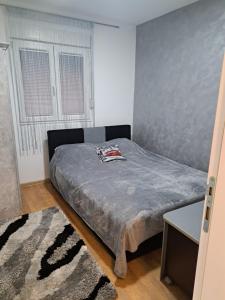 um quarto com uma cama com uma colcha cinzenta em Apartman Sara 2 em Novi Grad