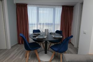 ein Esszimmer mit einem Tisch und blauen Stühlen in der Unterkunft Olimp Sea View Apartments Etajul 10 in Olimp