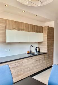 una cocina con armarios de madera y fregadero en Project Comfort Apartament Jana Kazimierza 17/47 Wola, en Varsovia