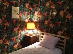 ein Schlafzimmer mit Blumentapete, einem Bett und einer Lampe in der Unterkunft Chambres d Hôtes Les Filles Tresy in Passenans
