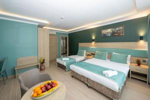 a hotel room with two beds and a table with a bowl of fruit at The Hotel Ottoman City Istanbul in Istanbul