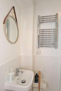 a white bathroom with a sink and a mirror at The Cabin at Gabriel House in Ilfracombe