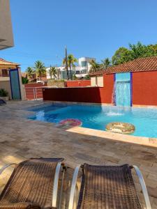 uma piscina com duas cadeiras em frente em Hotel Rosa da Ilha - Pertinho do Mar com piscina no Guarujá