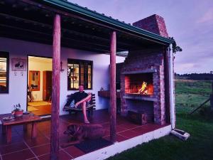 a person sitting on a bench in front of a fireplace at Hermitage Huisies in Swellendam