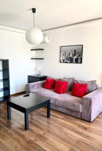 una sala de estar con un sofá púrpura con almohadas rojas en Project Comfort Apartament Jana Kazimierza 17/47 Wola, en Varsovia