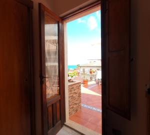 una puerta abierta a un balcón con vistas al océano en Terrazza Lungomare en Caronia Marina